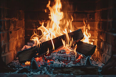 Brennendes Holz mit Flammen und Glut in einem gemauerten Kamin