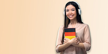 Studentin, die ein Buch in der Hand hält, das mit den Farben der Deutschlandfahne symbolisieren soll, das sie Deutsch lernt
