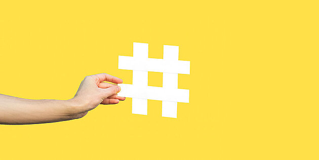 Gelber Hintergrund: Hand, die das Rautenzeichen hält