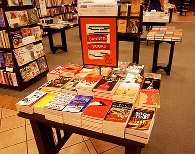 Bücher auf einem Tisch in einer Buchhandlung mit einem Schild 'BANNED BOOKS'